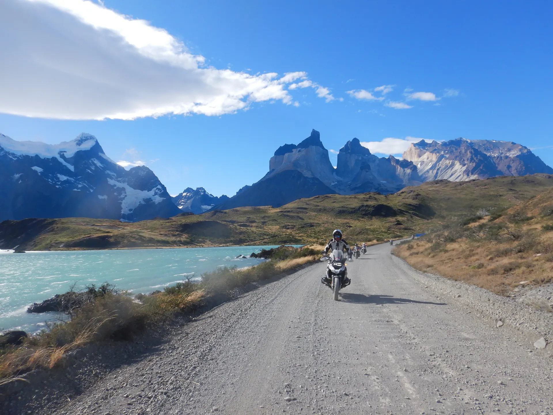 Motociclistas en un camino de ripio junto al lago Pehoé, con los Cuernos del Paine al fondo, Patagonia chilena