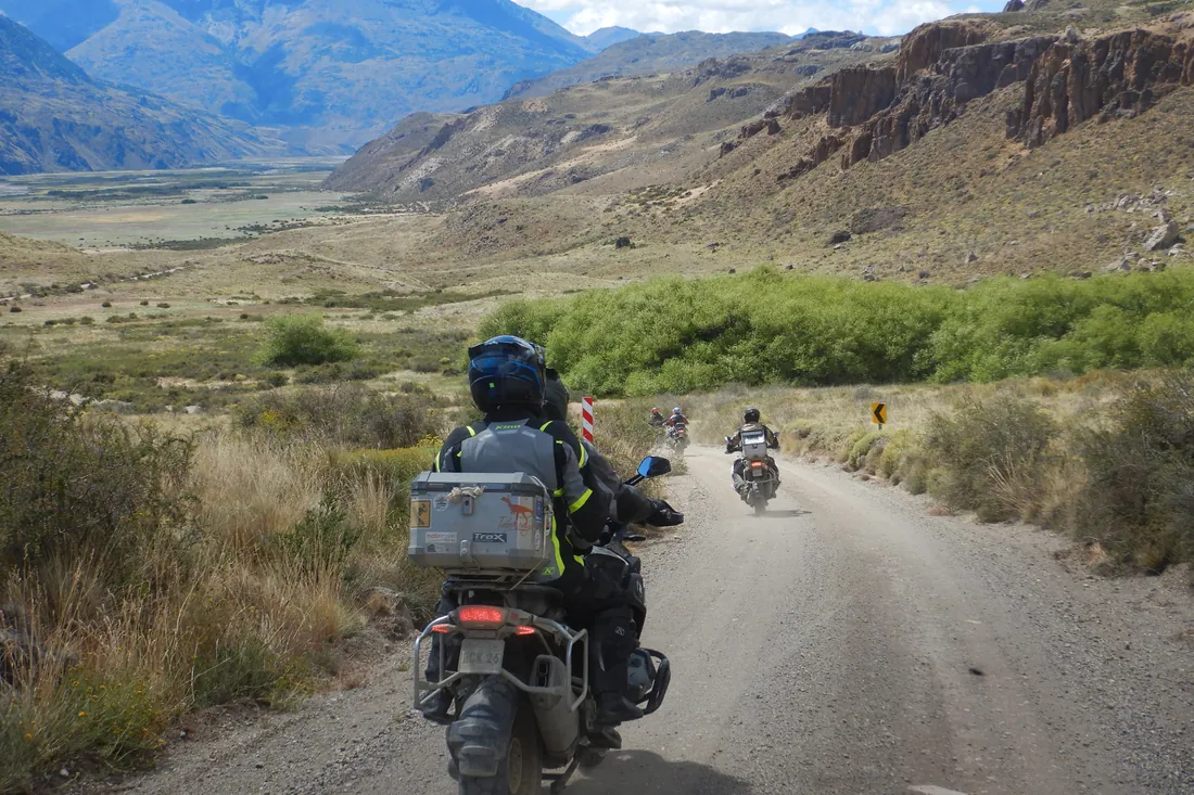 Grupo de motociclistas de MotoTravel en un camino de ripio por un valle de la Patagonia